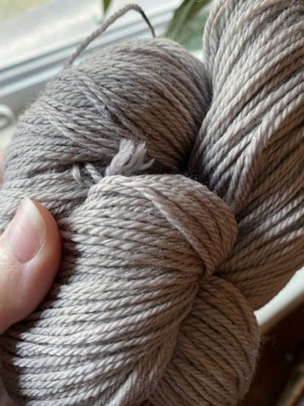 Grey yarn hand dyed with natural dye made from avocado skins and iron.